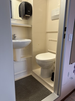 Een kleine, praktische badkamer met een witte wastafel, toilet en een handdroger bevestigd aan de muur.