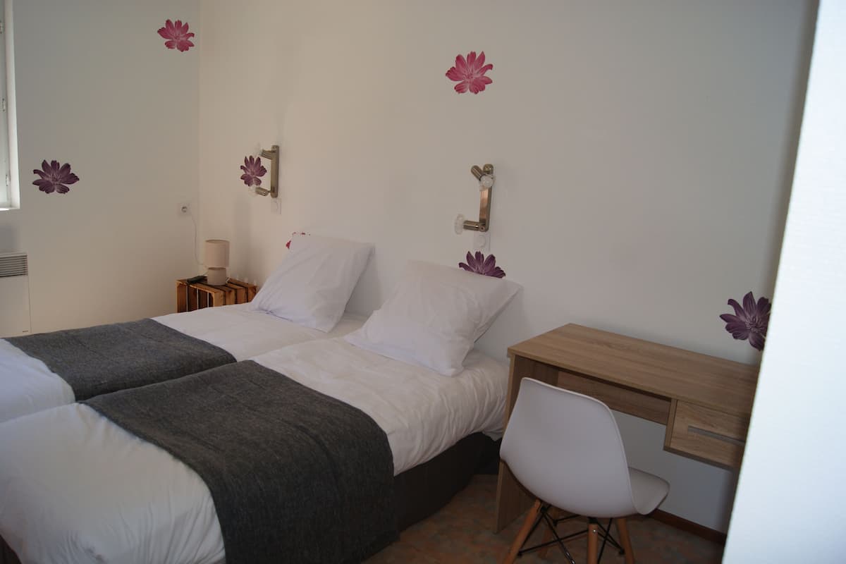 Een hotelkamer met twee bedden, een bureau en een stoel.