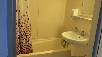 A bathroom with a bathtub, sink, toilet, and a shower curtain.