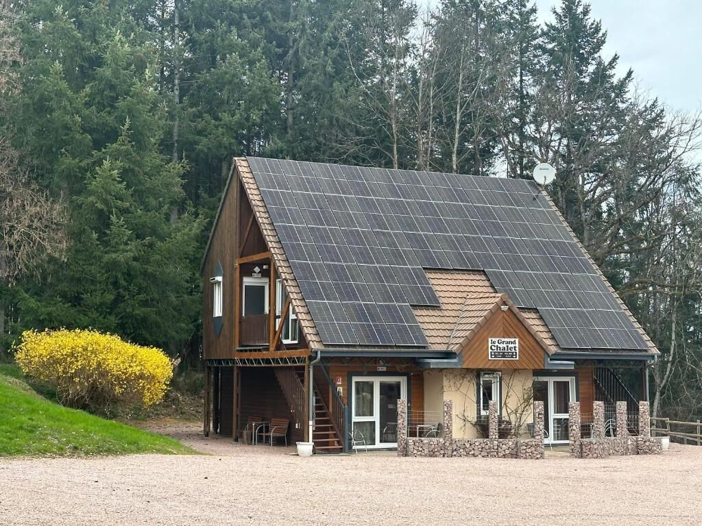A wooden building with a sloped roof, solar panels, and a sign that reads 'Le Grand Chalet.'