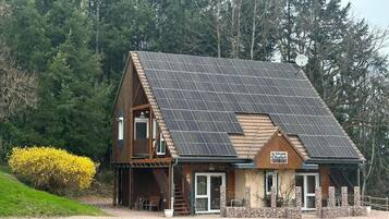 A wooden building with a sloped roof, solar panels, and a sign that reads 'Le Grand Chalet.'