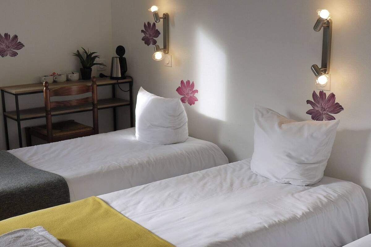 Een hotelkamer met twee bedden, een bureau en wandlampen.