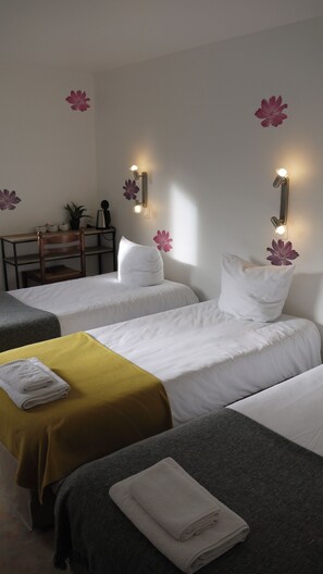 Een hotelkamer met twee bedden, een bureau en wandlampen.
