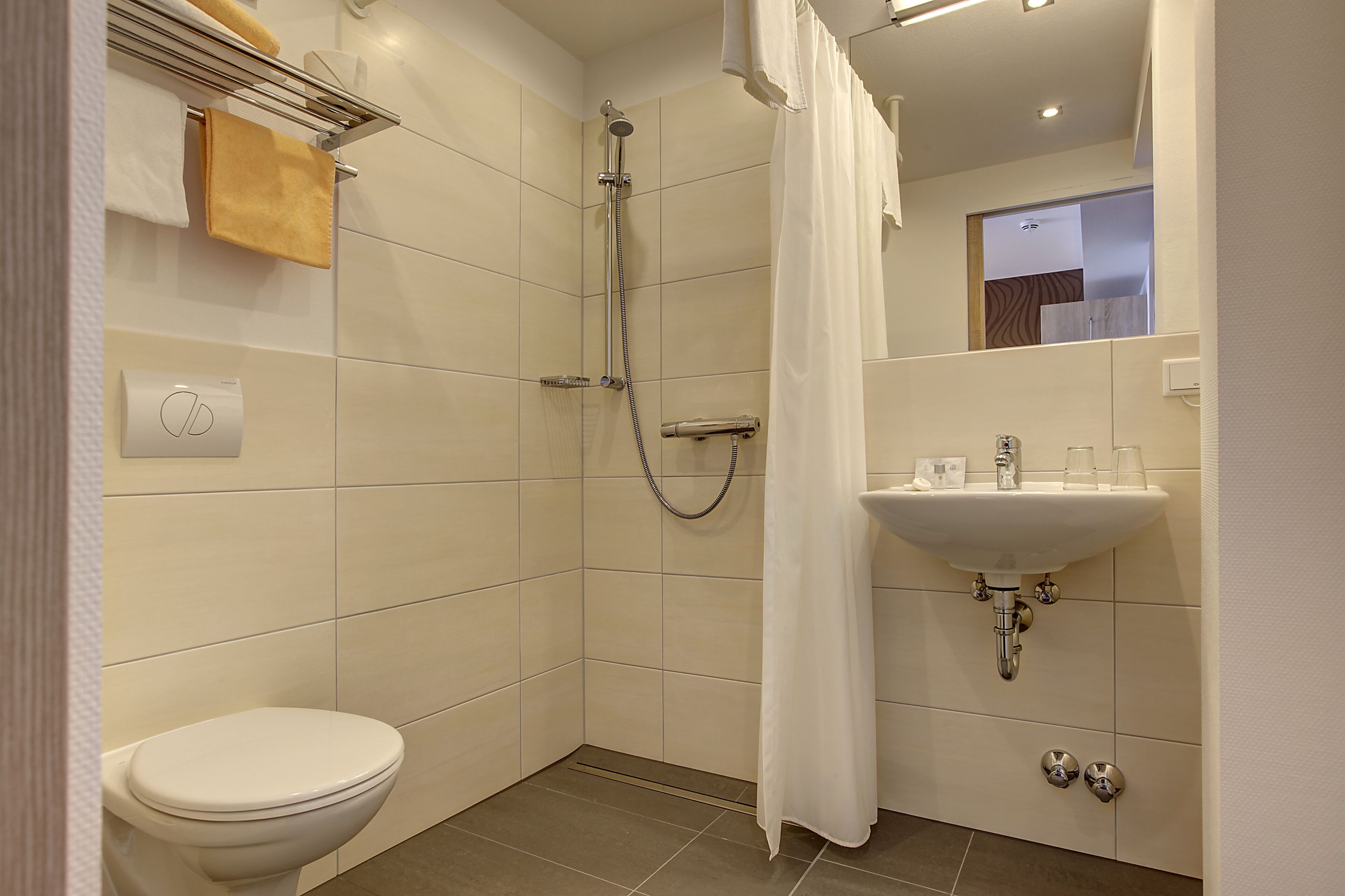 A modern bathroom with a toilet, shower, and sink.