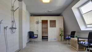 Casa de banho moderna com duche, duas cadeiras, sauna de madeira e clarabóia.