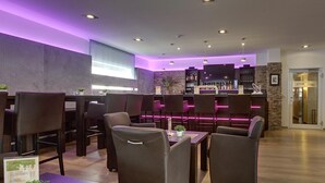 Um espaço de bar moderno com cadeiras de couro escuro, balcão com parede de destaque em pedra e iluminação roxa ambiente.