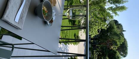 A table set outdoors with a fork, a bowl of food, and a wine glass.