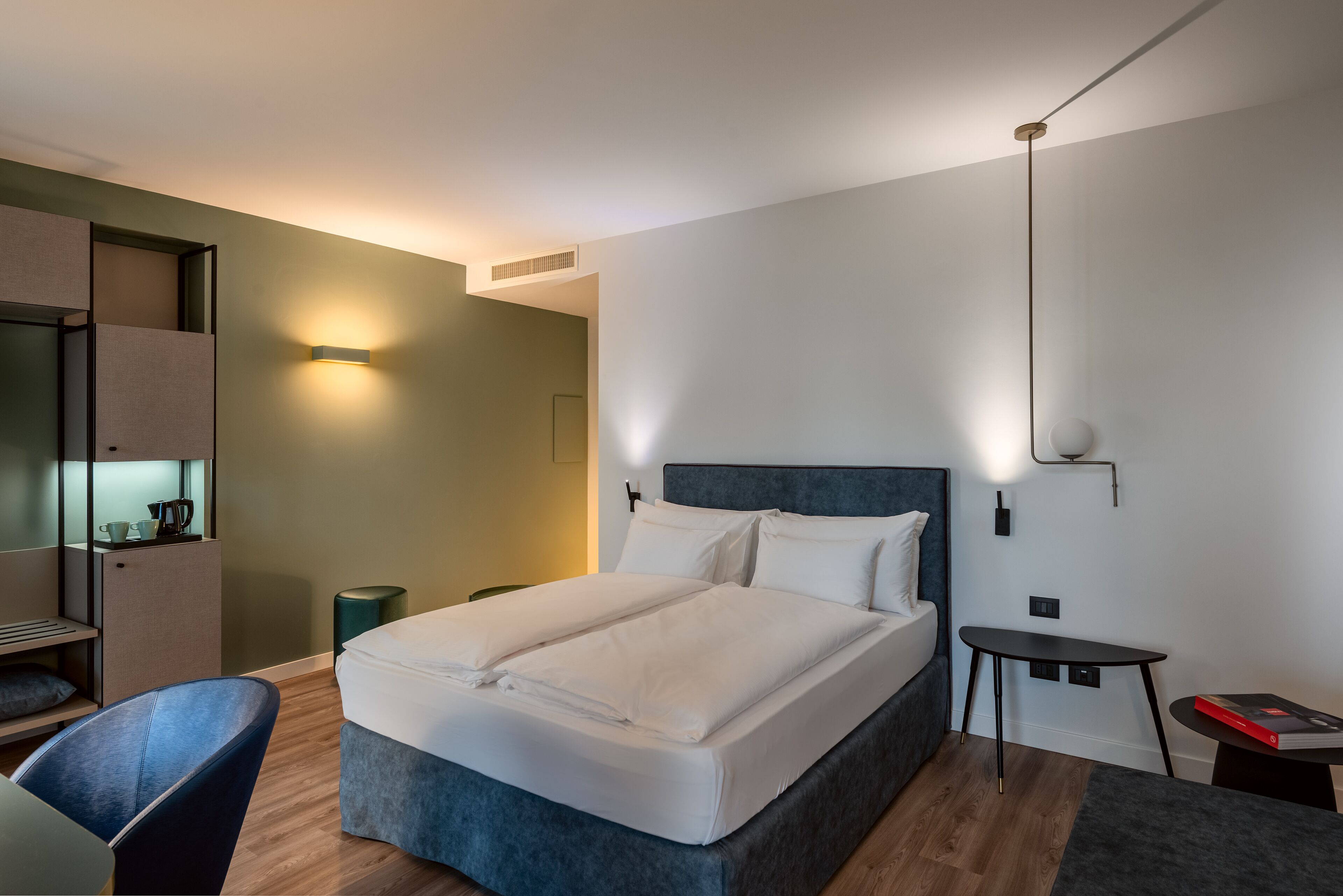Una habitación de hotel moderna con una cama grande, un escritorio, una silla y una mesita.