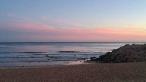 A beach with a rocky shoreline and calm sea.