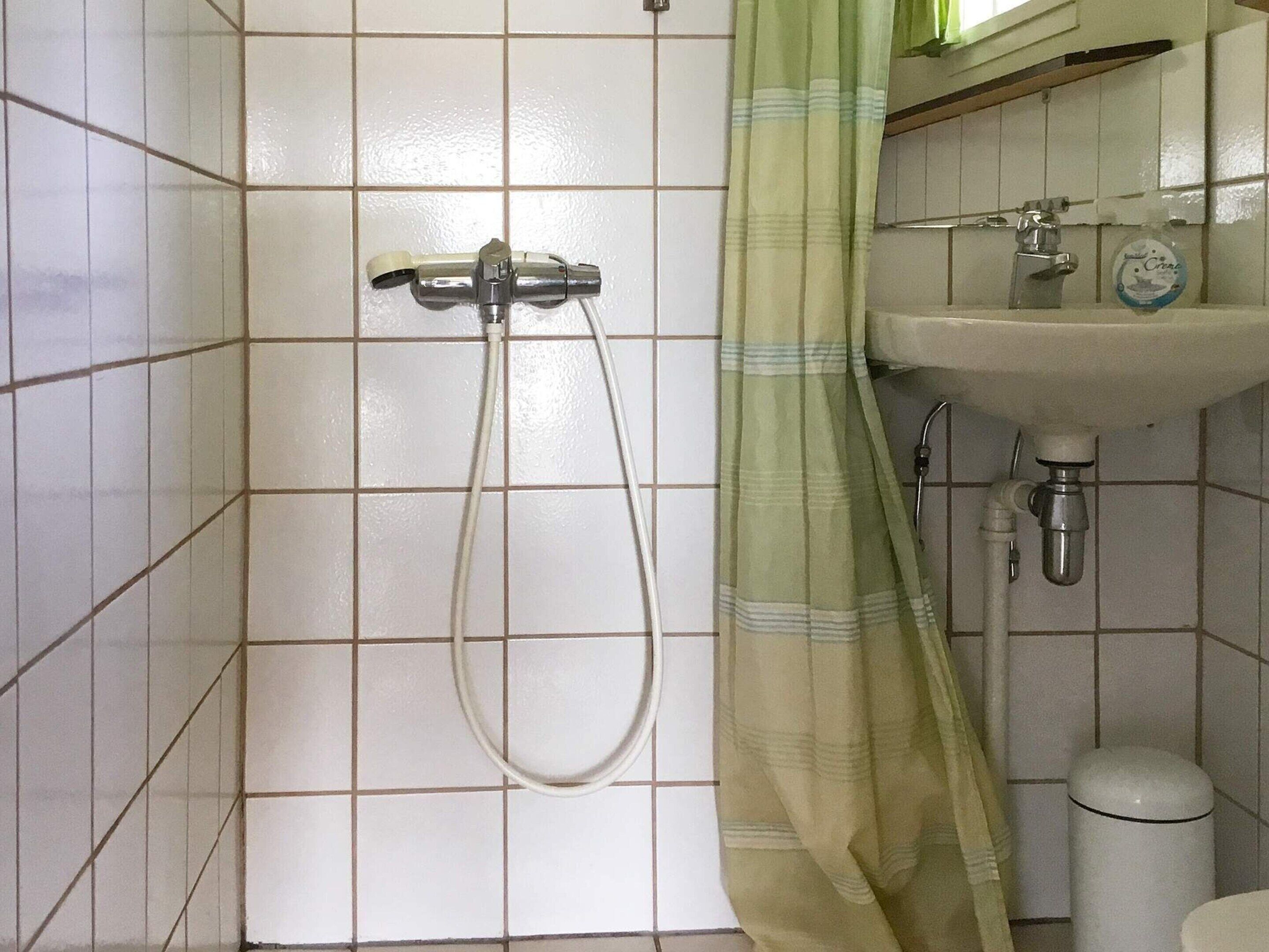 Et badeværelse med brusebad, vask og toilet.