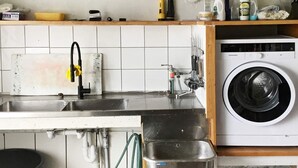Una cucina con lavatrice, lavandino e diversi oggetti da cucina sul piano di lavoro.