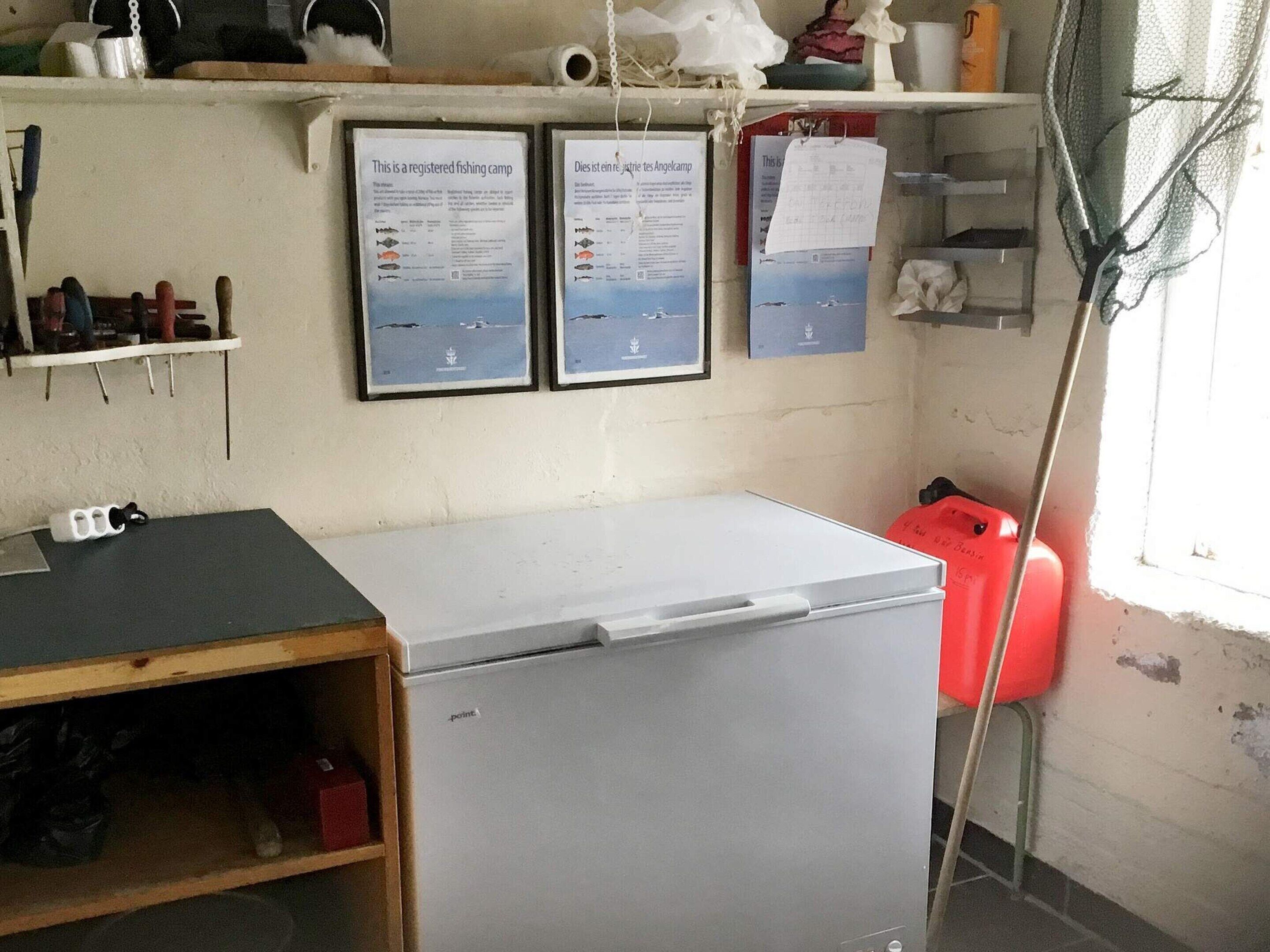 A small kitchen with a refrigerator, a sink, and a shelf with various items.