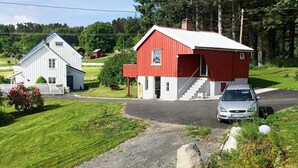 Paesaggio rurale con un edificio rosso e bianco, una casa bianca e un vialetto sterrato.