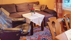 Un accogliente soggiorno con un divano in pelle marrone, un tavolino con tovaglia bianca e un tappeto decorato.