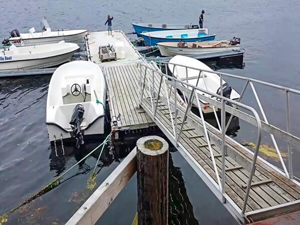 A dock with several boats moored, a wooden walkway, and a person standing on the dock. - 15 Person Holiday Home in Flatanger (Flatanger)