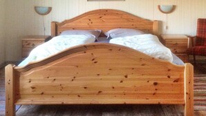 Un letto in legno con testiera, due comodini, una sedia e un quadro appeso al muro.