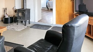 Un soggiorno con un divano in pelle nera, una televisione e un camino a legna.