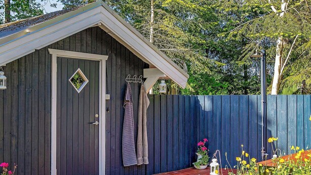 A wooden shed with a door, a small window, and a wooden deck. - 6 Person Holiday Home in Roslev-by Traum (Roslev)