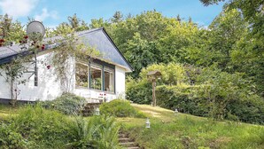 A house with a satellite dish, surrounded by lush greenery and a stone staircase leading to the entrance. - 6 Person Holiday Home in Roslev-by Traum (Roslev)