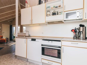 A modern kitchen with white cabinetry, a built-in oven, a microwave, and a coffee machine. - 4 Star Holiday Home in Borkop (Borkop)