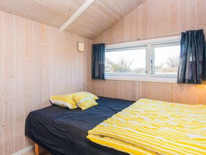 A small, cozy room with wooden walls, a single bed with a black and yellow striped blanket, and a window with dark curtains. - 4 Star Holiday Home in Borkop (Borkop)