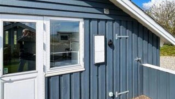 Un edificio con una ventana, una puerta y un objeto rectangular pequeño en la pared.