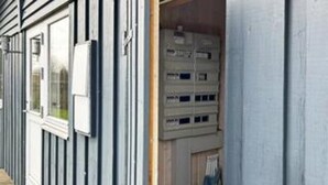 Un edificio con una ventana, una puerta, un cuadro de electricidad y una pared con un diseño vertical.