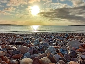 A rocky beach with a sunset over the water. - 4 Star Holiday Home in Borkop (Borkop)