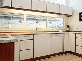Una cocina con gabinetes blancos, un lavamanos de acero inoxidable y un lavavajillas Bosch.