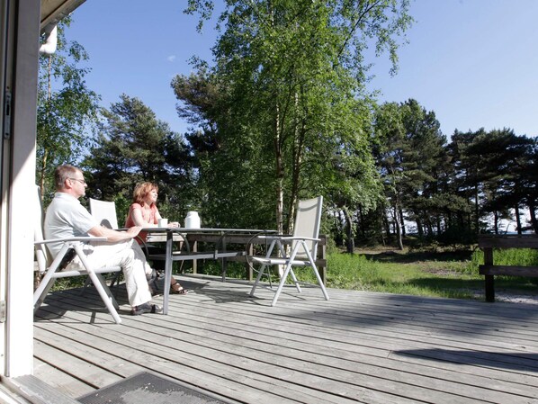 A wooden deck with a table and chairs, surrounded by trees.