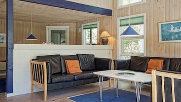 Un interior moderno con un sofá de cuero negro, una mesa blanca y una alfombra azul.