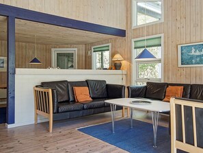 A modern interior with a black leather sofa, a white table, and a blue rug. - 14 Person Holiday Home in Nexo (Nexø)