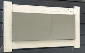 Une fenêtre à cadre blanc avec un volet gris.