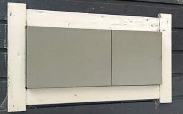 A white-framed window with a grey shutter.