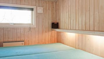 Una habitación con paredes de madera, una ventana, una cama y un estante con un altavoz.
