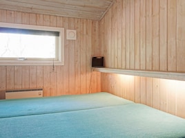Una habitación con paredes de madera, una ventana, una cama y un estante con un altavoz.