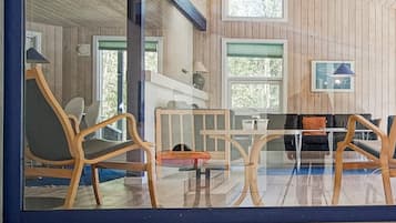 Una habitación con paredes de madera, un separador de vidrio y una zona de estar con sillas y una mesa.