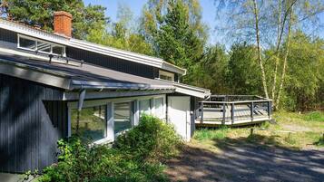 Et moderne hus med en overdækket veranda og en træterrasse.