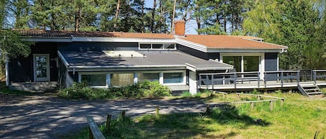 Une maison à deux étages avec un toit plat, de grandes fenêtres et une terrasse.