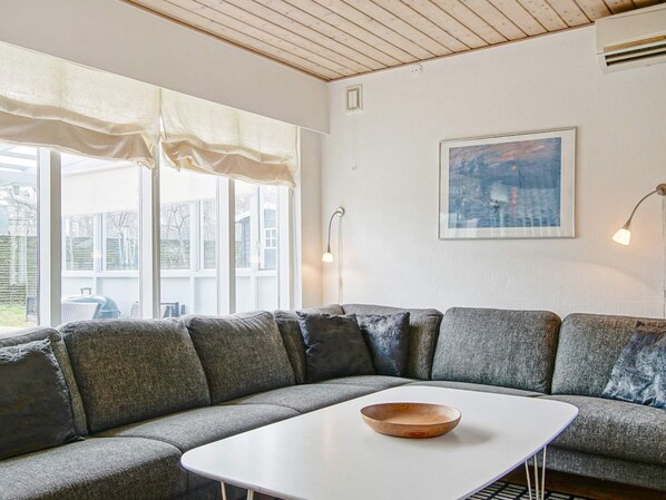 A modern living room with a grey sectional sofa, a white coffee table, and a framed artwork on the wall.