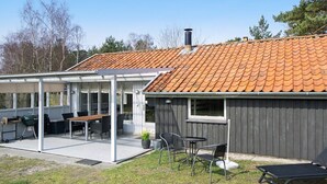Uma casa com varanda coberta, área de estar externa e chaminé.