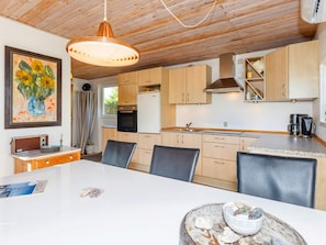 A compact kitchen with wooden cabinets, a built-in oven, and a coffee maker. - Pet-friendly Holiday Home in Roslev near Sea (Roslev)