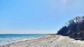 Una playa con cielo despejado y mar tranquilo.