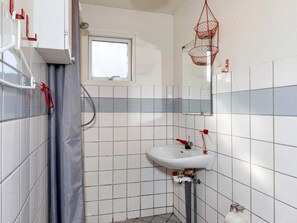 A bathroom with a white sink, a window, and a shower area.