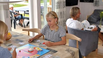 En gruppe mennesker spiller et brætspil ved et bord med et Monopoly-spil og penge.