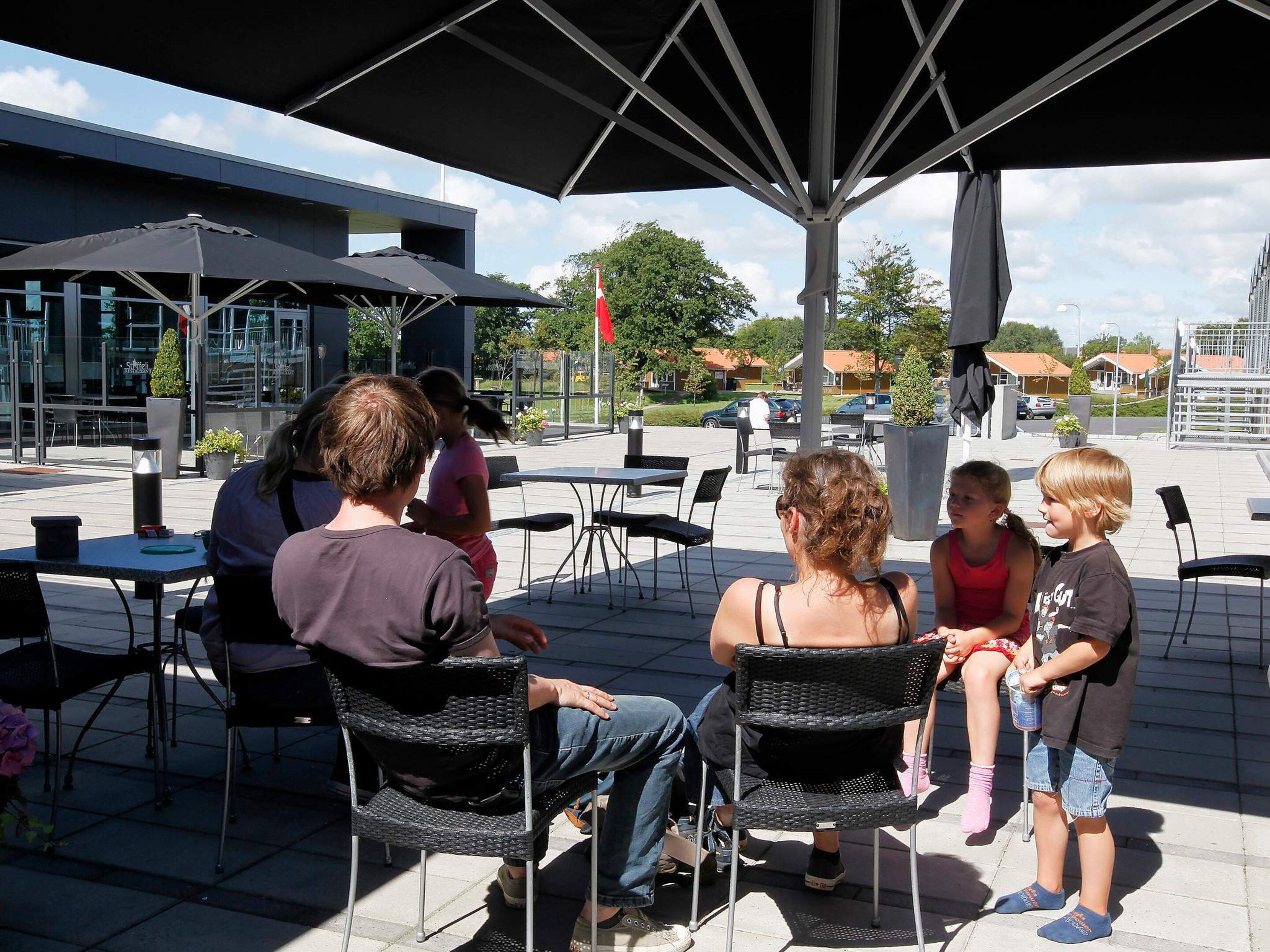 Un espace extérieur aménagé avec des tables et des chaises, protégé par un grand parasol.