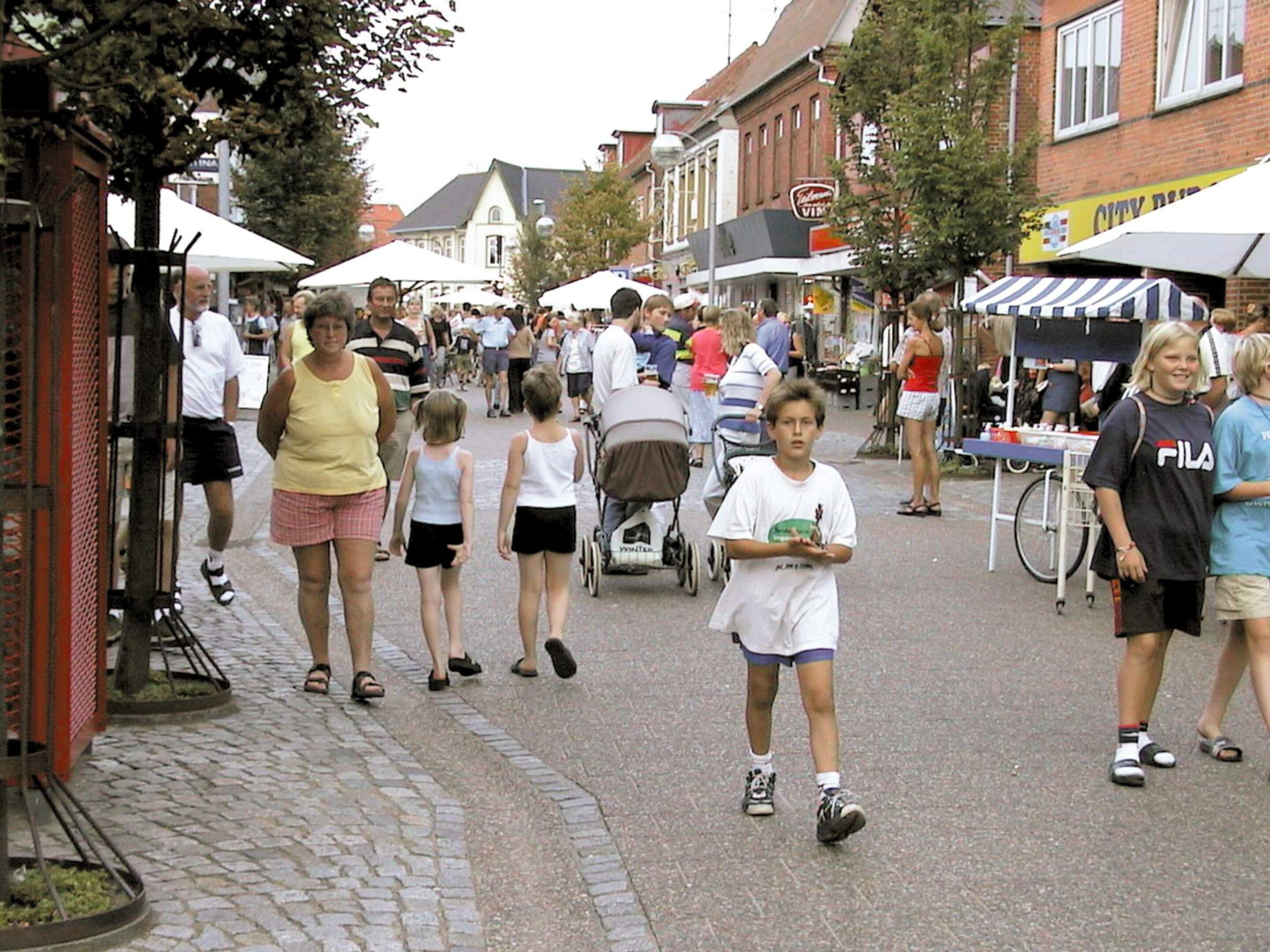 A cobblestone street lined with buildings, a stroller, and people walking.