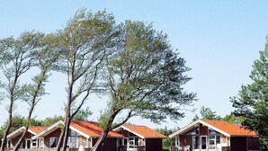 Une rangée de cabanes aux toits rouges, entourées d’arbres et de zones herbeuses.