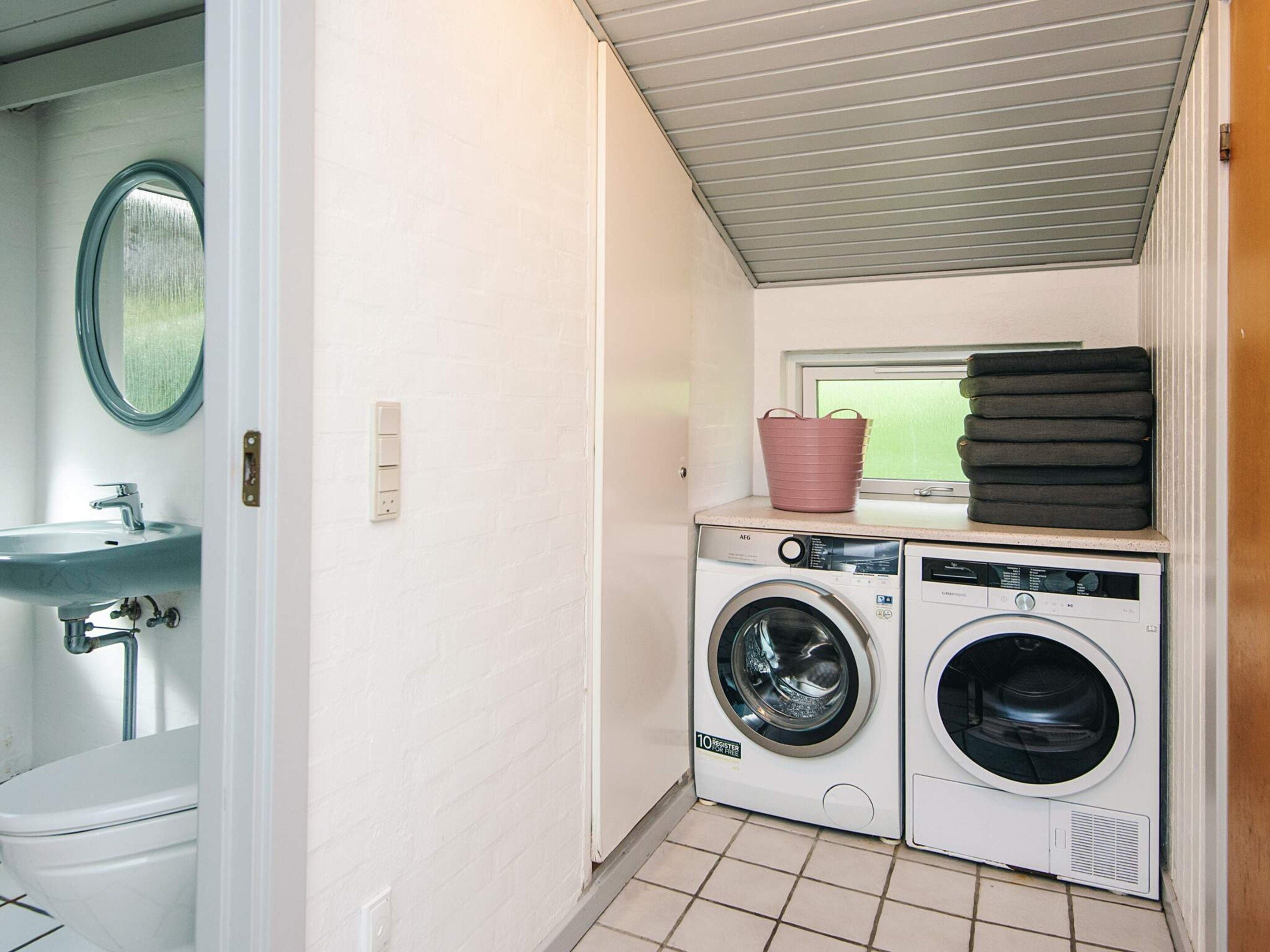 Een kleine wasruimte met een wasmachine, droger en een wasbak.
