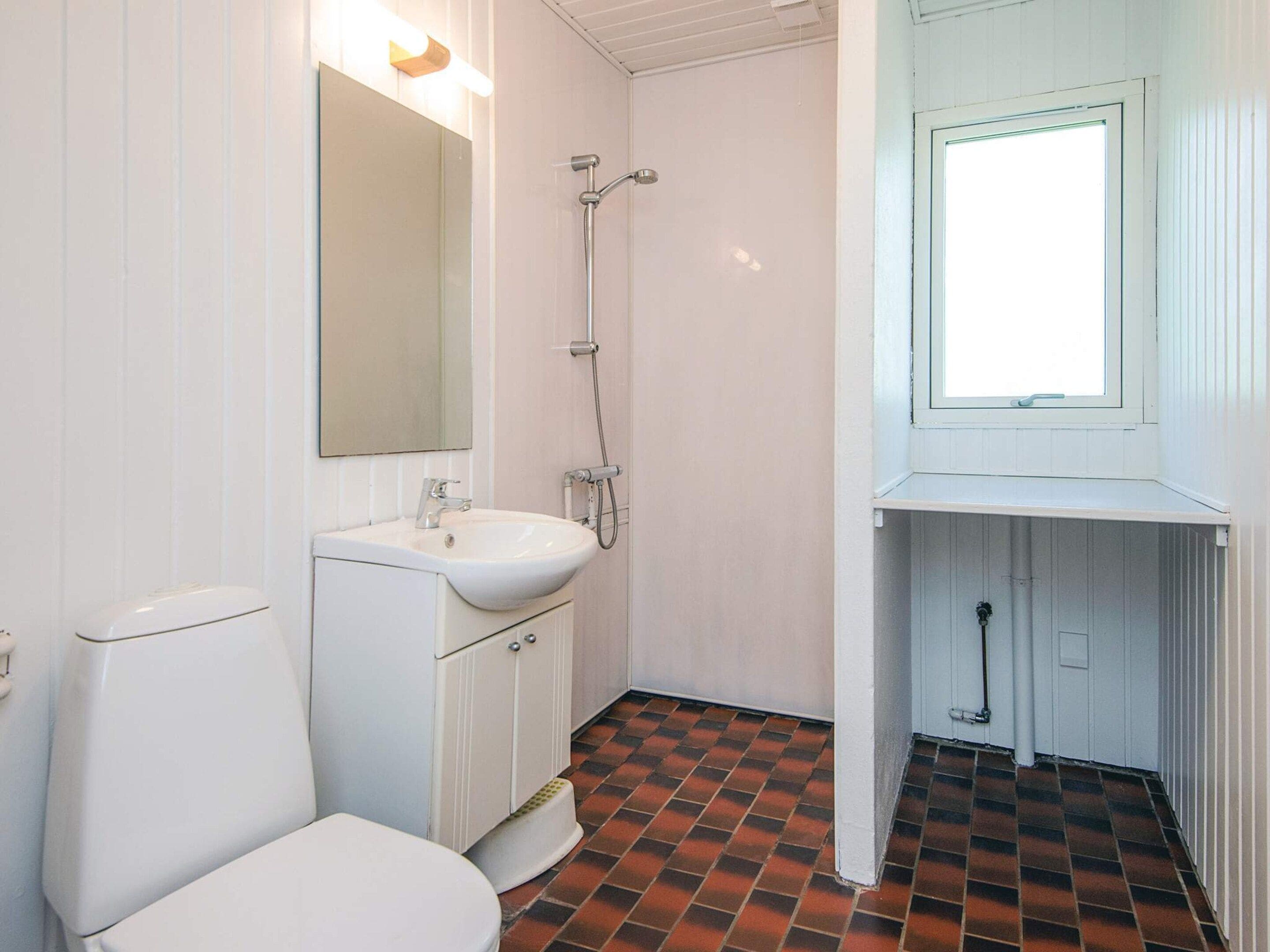 Et badeværelse med toilet, håndvask og brusebad.